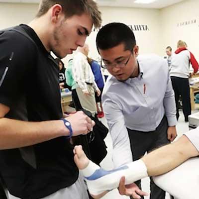 Athletic training student wrapping an injured ankle